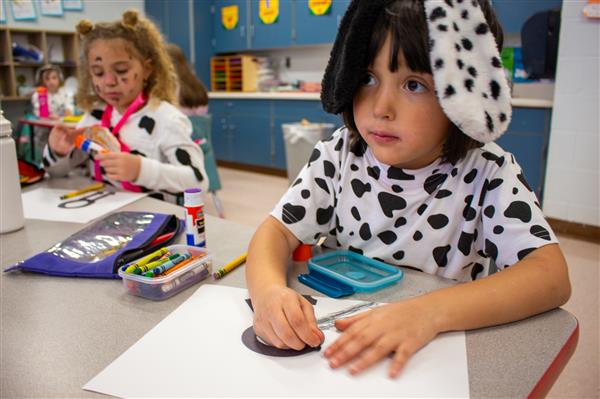 two students dressed as dalmatian dogs sitting at desks
